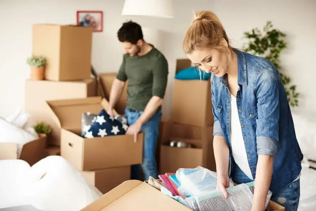 Couple packing boxes in a living room.